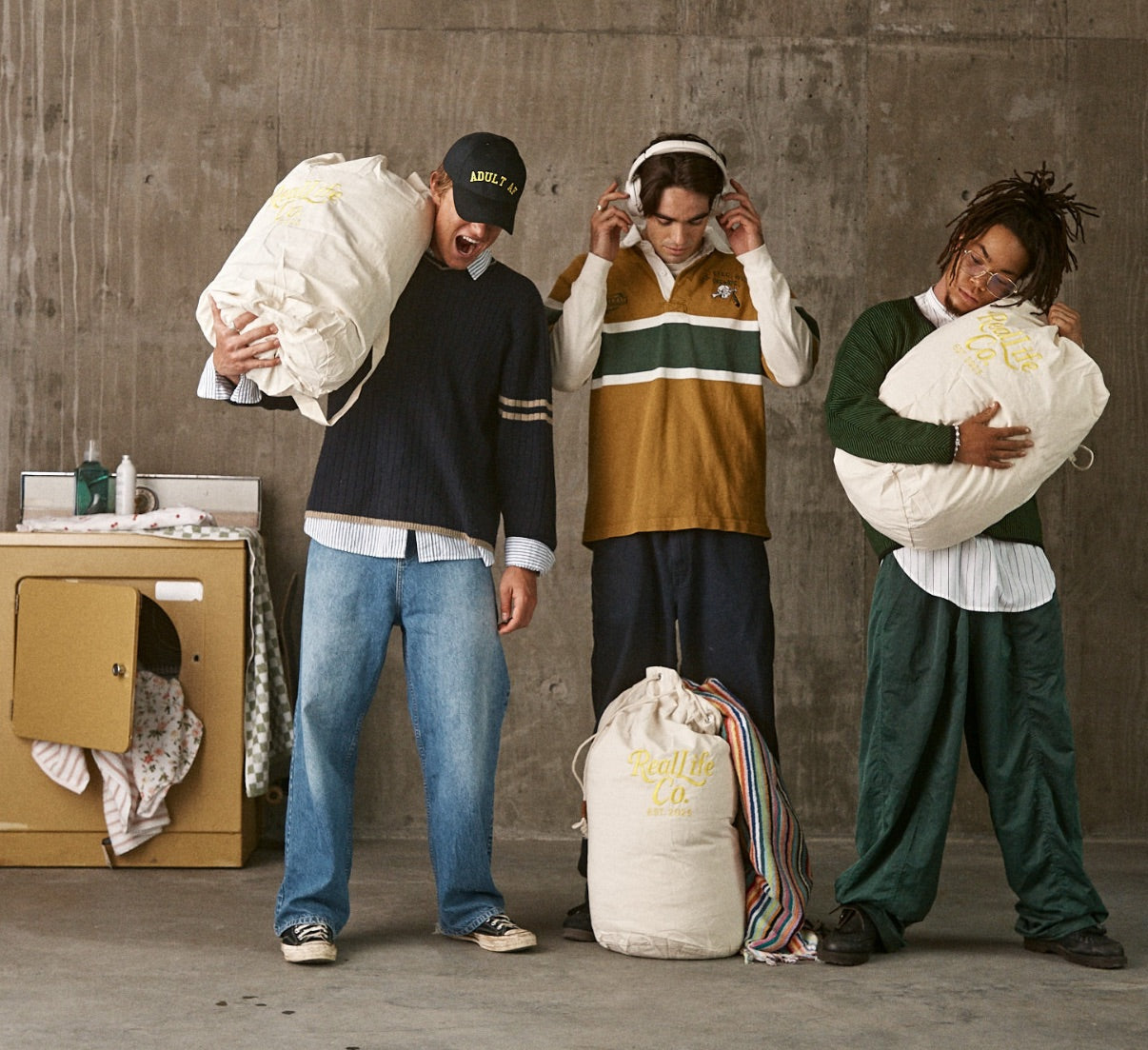 Three people holding large bags labeled 'Kuji' in a casual setting.